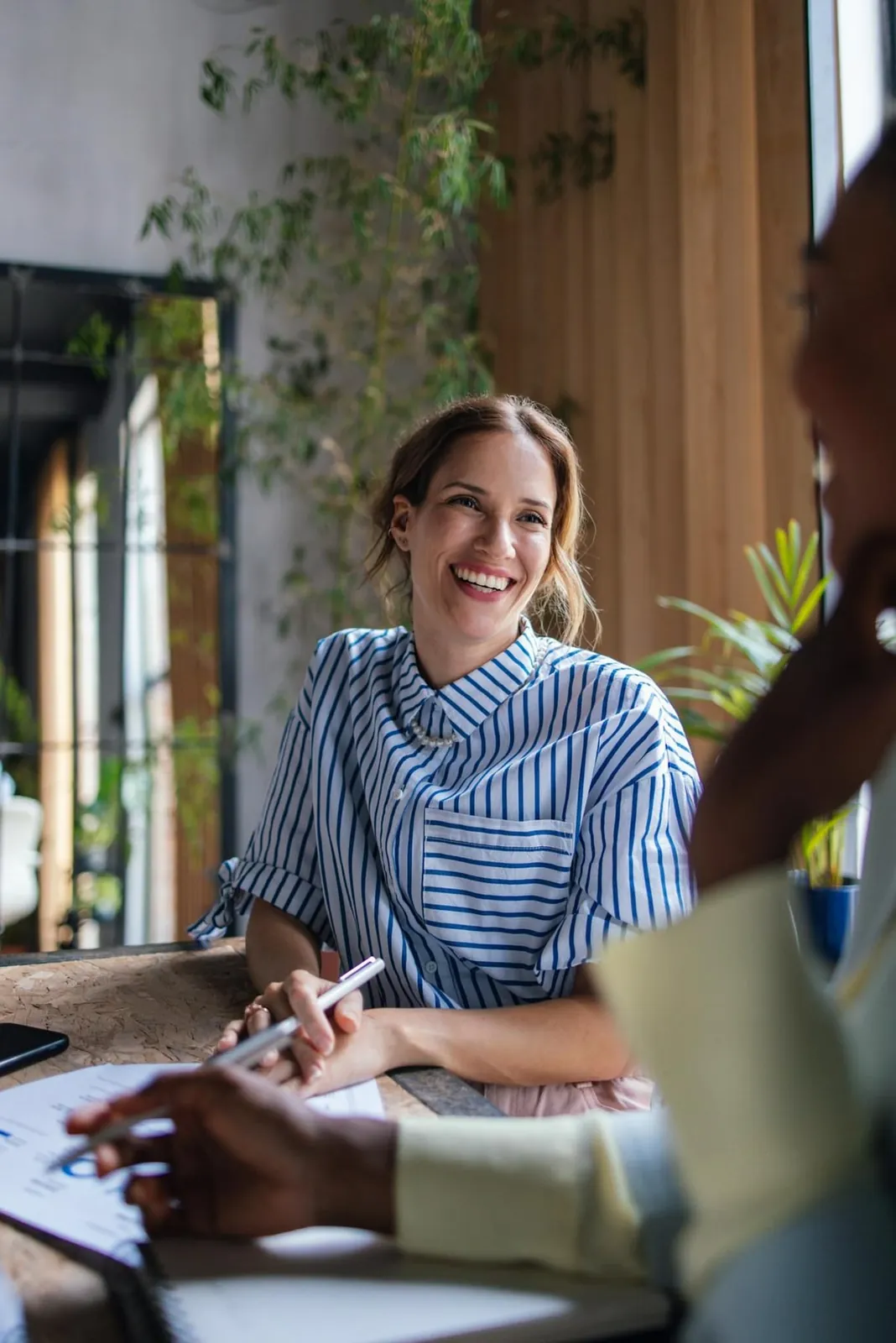 A smiling member of staff in conversation with a colleague across a table of notes